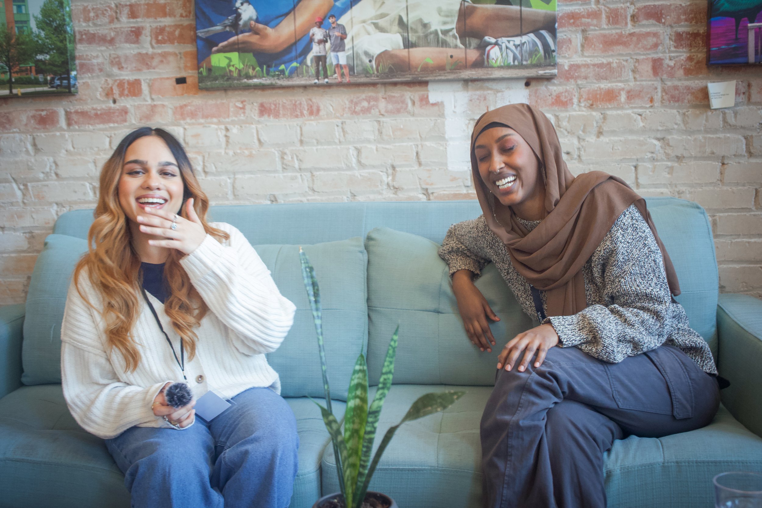DSC00613 Two BIPOC women smiling and laughing while conversing in a cozy interview setting.